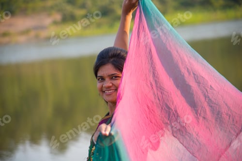 Preview: Young happy Indian girl playing with her pink scarf at outdoor.