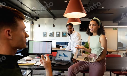 Preview: Multiracial male and female colleagues discussing plan over laptop in meeting at office