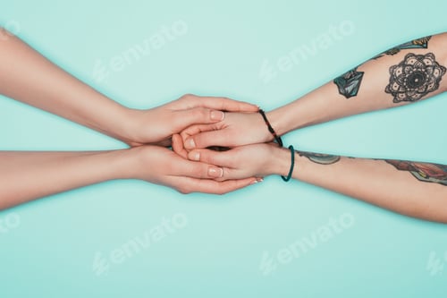 Preview: cropped shot of sensual women holding hands of each other isolated on turquoise