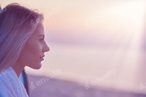 Preview: Silhouette of young woman practicing yoga on the beach at sunrise