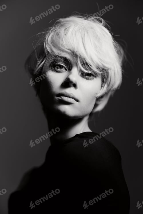 Preview: Elegant young woman with short blonde hair, posing confidently in a dark setting, exuding a