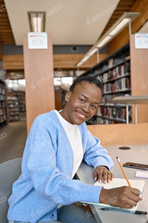 Preview: Happy African girl college student learning in library. Vertical portrait.