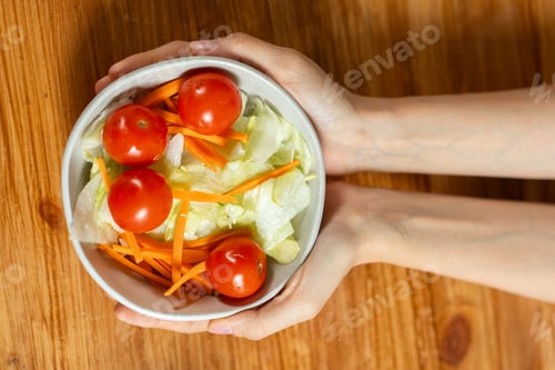Preview: Vegetable Salad Bowl Held Over Wooden Table
