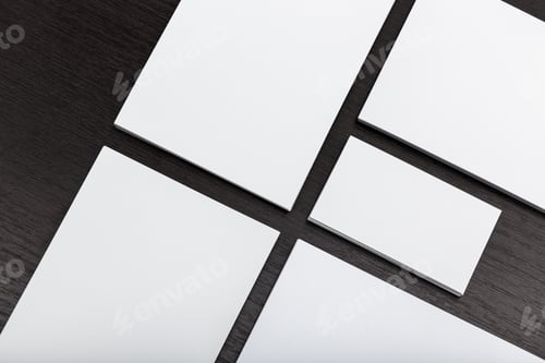 Preview: Blank white stationery laid out on a dark wooden surface for design or branding purposes