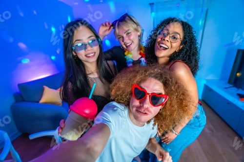 Preview: Friends taking selfie at home disco party with colorful lights and drinks