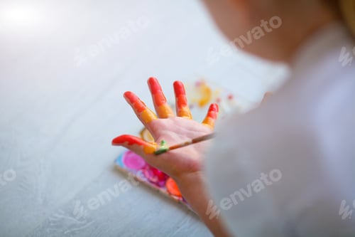 Preview: Child girl sitting on the floor and paints the palm of his hand. Quarantine.