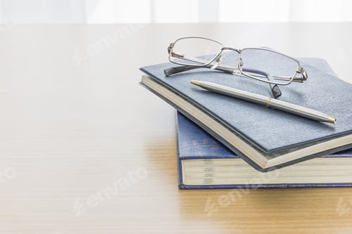 Preview: Black book with glasses and pen