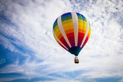 Preview: Bright and colorful hot air balloon in the sky. Bright blue sky with a few clouds.