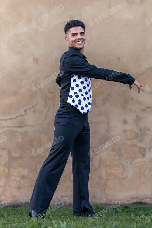 Preview: full-length portrait of a smiling flamenco dancer dressed in black with a polka-dotted waistcoat