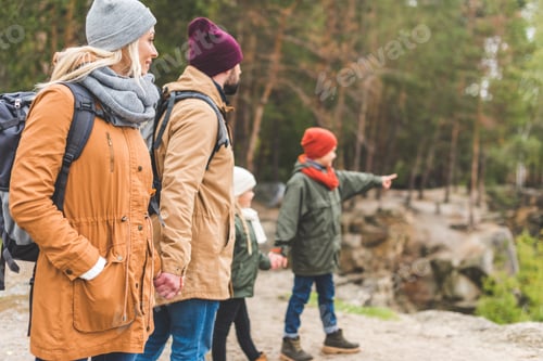 Preview: selective focus of family holding hands together while standing in autumn forest