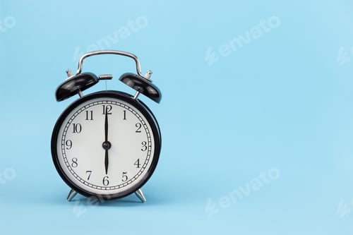 Preview: A black alarm clock with a round dial stands on a blue background with free space for text