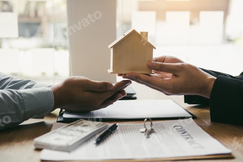 Preview: Real estate agent congratulations to new buyer by giving house model to client in the agency office.