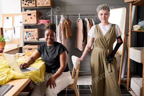 Preview: Two young successful female tailors or fashion designers looking at camera