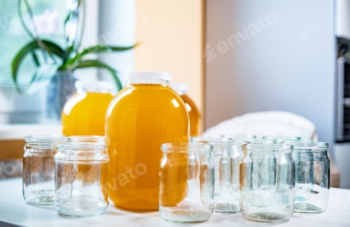 Preview: Composition of a large number of jars and three jars of honey standing on a white table against a