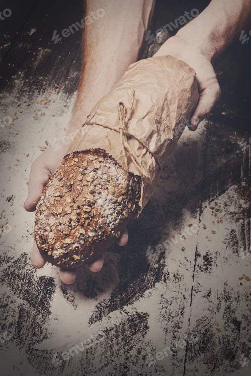 Preview: Bakery concept background. Hands hold bread loaf