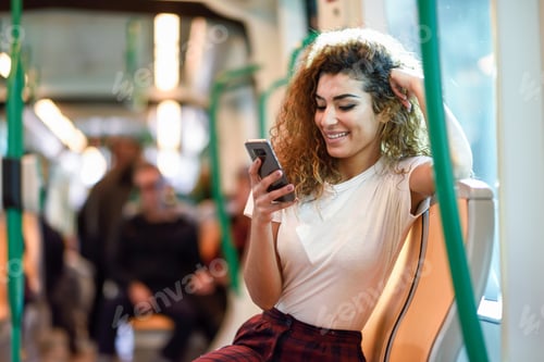 Preview: Arab woman inside subway train looking at her smartphone