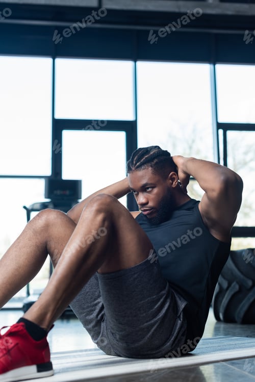 Preview: focused young african american sportsman doing abs in gym