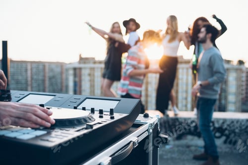 Preview: Group of friends enjoying roof party, young man using mixing desk