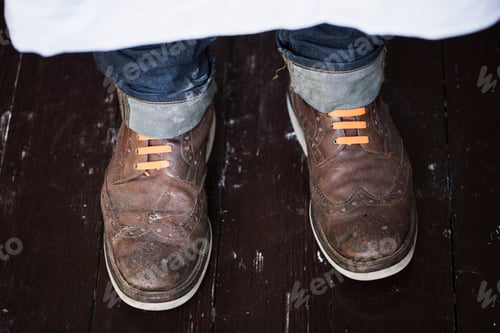 Preview: Close up of a man's feet, wearing brown shoes with orange shoe laces.