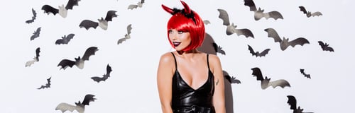 Preview: panoramic shot of girl in devil Halloween costume near white wall with decorative bats