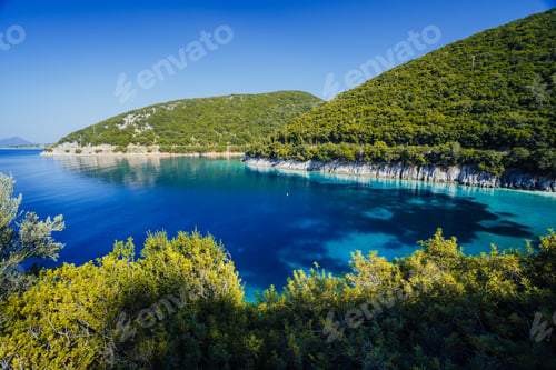 Preview: Stunning seaside scenery of the cove with turquoise calm sea water, surrounded by hills overgrown