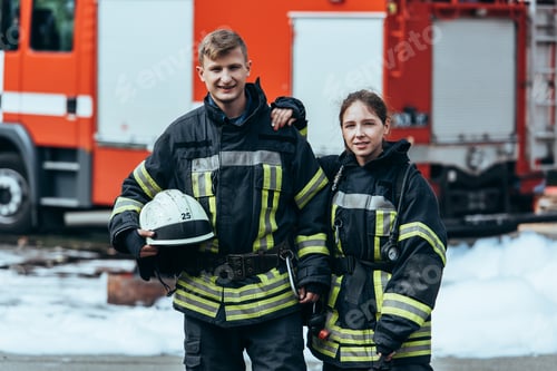 Preview: portrait of firefighters in fireproof uniform standing on street with fire truck behind