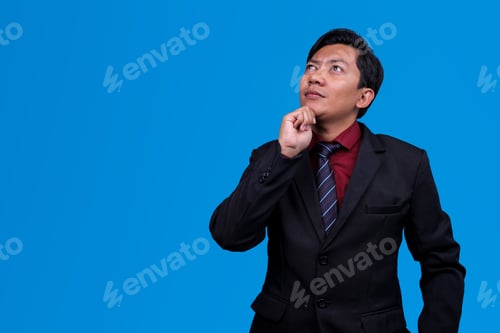 Preview: Businessman Look Up While Thinking Against Blue Background