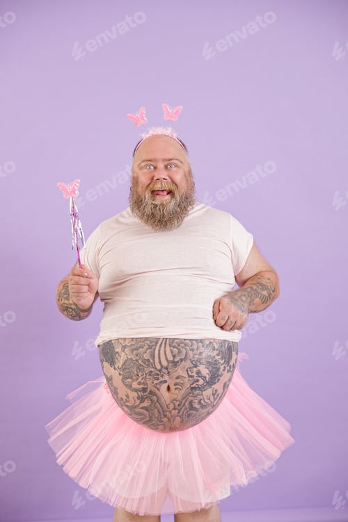 Preview: Funny plus size man in fairy costume holds magic stick on purple background