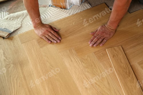 Preview: High angle shot of a worker installing wooden parquet laminate flooring