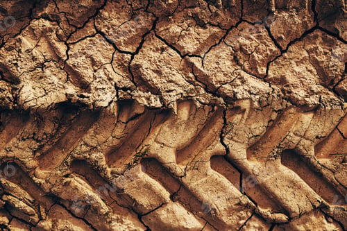 Preview: Agricultural tractor tire tread marks in dried mud forming a distinctive pattern on a dirt road