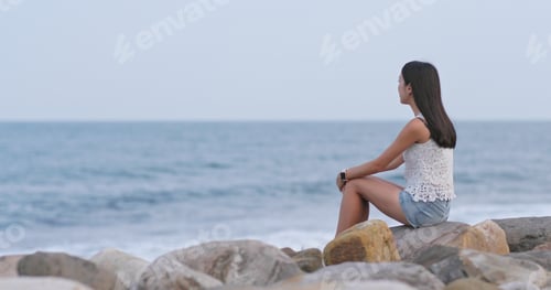 Preview: Woman sitting at the seaside and look far away