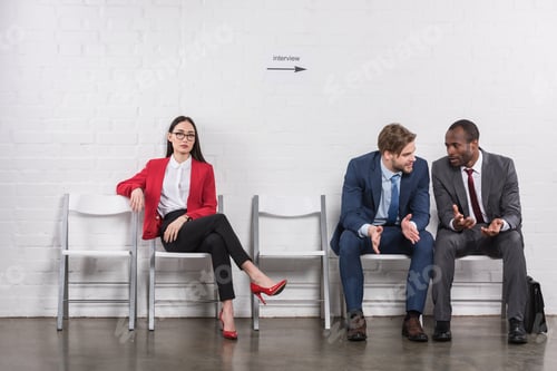 Preview: multicultural businessmen having conversation near asian businesswoman while waiting for job