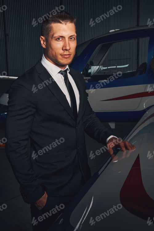 Preview: Handsome young man standing by aircraft in airport hangar