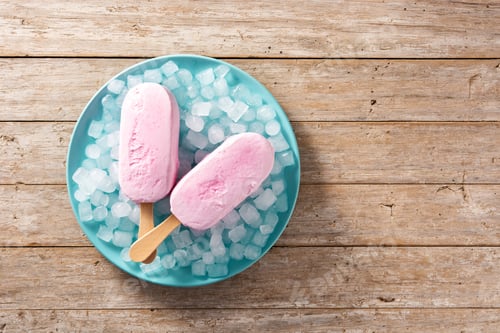 Preview: Strawberry popsicles and crushed ice on blue plate