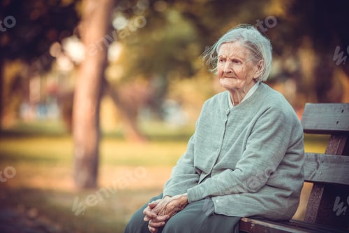 Preview: Portrait of senior woman sitting on bench in autumn park.