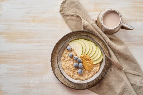 Preview: Oatmeal, healthy porridge in large bowl with fruits and berry for breakfast, cup of cocoa.