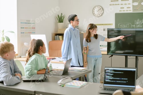 Preview: Teenage Asian Girl Explaining Coding Project to Diverse Classmates in Classroom