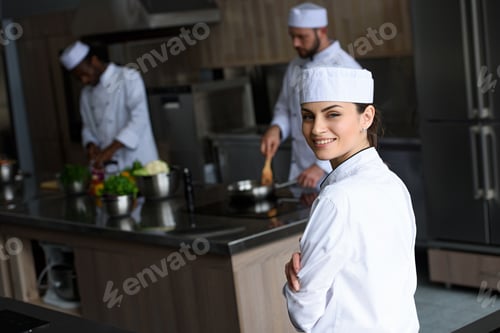 Preview: smiling beautiful chef looking at camera at restaurant kitchen