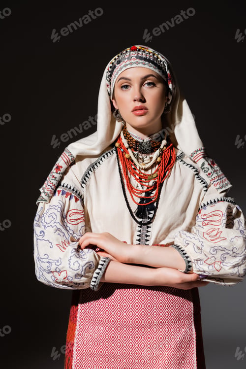 Preview: young ukrainian woman in traditional shirt with ornament and red beads posing on black