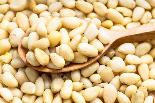 Preview: wood spoon with shelled pine nuts on pile of nuts