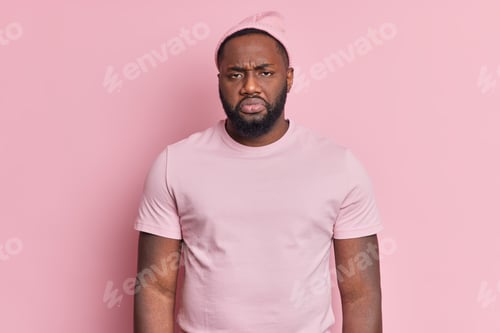 Vista previa: Photo of frustrated displeased bearded dark skinned man looks unhappily at camera being dissatisfied