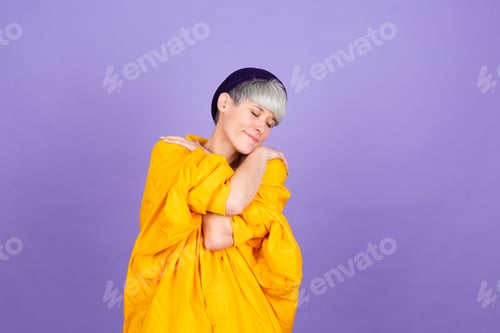 Preview: Stylish european woman on purple background self care hugging herself with smile and closed eyes