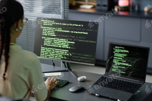 Preview: Female IT Programmer Coding on Computers Using Multiple Screens at Workstation in Office
