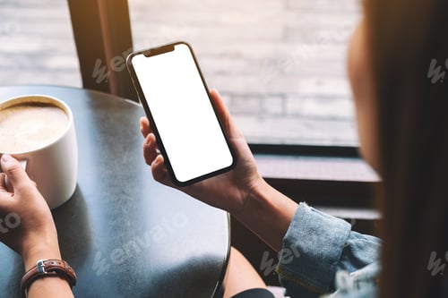 Preview: Mockup image of a woman holding black mobile phone with blank screen while drinking coffee