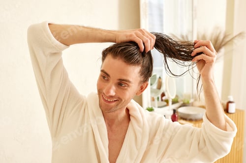 Preview: Man in bathrobe tying wet hair in bathroom