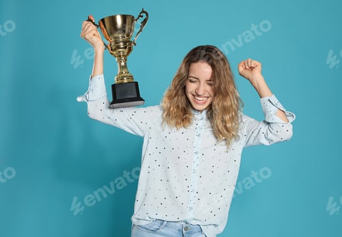 Preview: Portrait of happy young woman with gold trophy cup on blue background