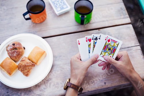 Preview: Close up of a man sitting at a table, holding playing cards.