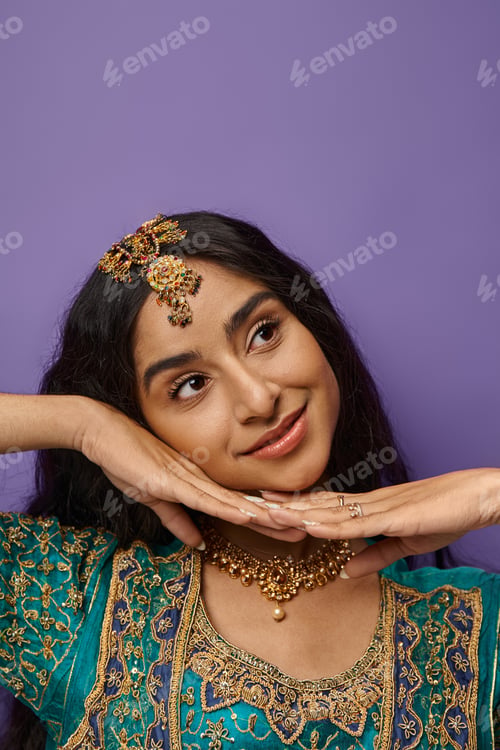 Preview: vertical shot of beautiful joyful indian woman posing with hands under chin and looking away