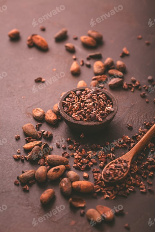 Preview: Organic cocoa nibs and cocoa beans in a bowl on brown background