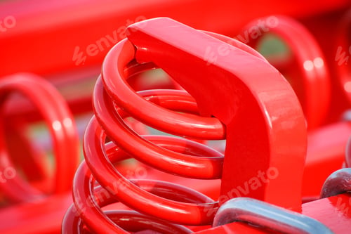 Preview: Big and hard red steel spring as part and detail of industrial or agricultural machine